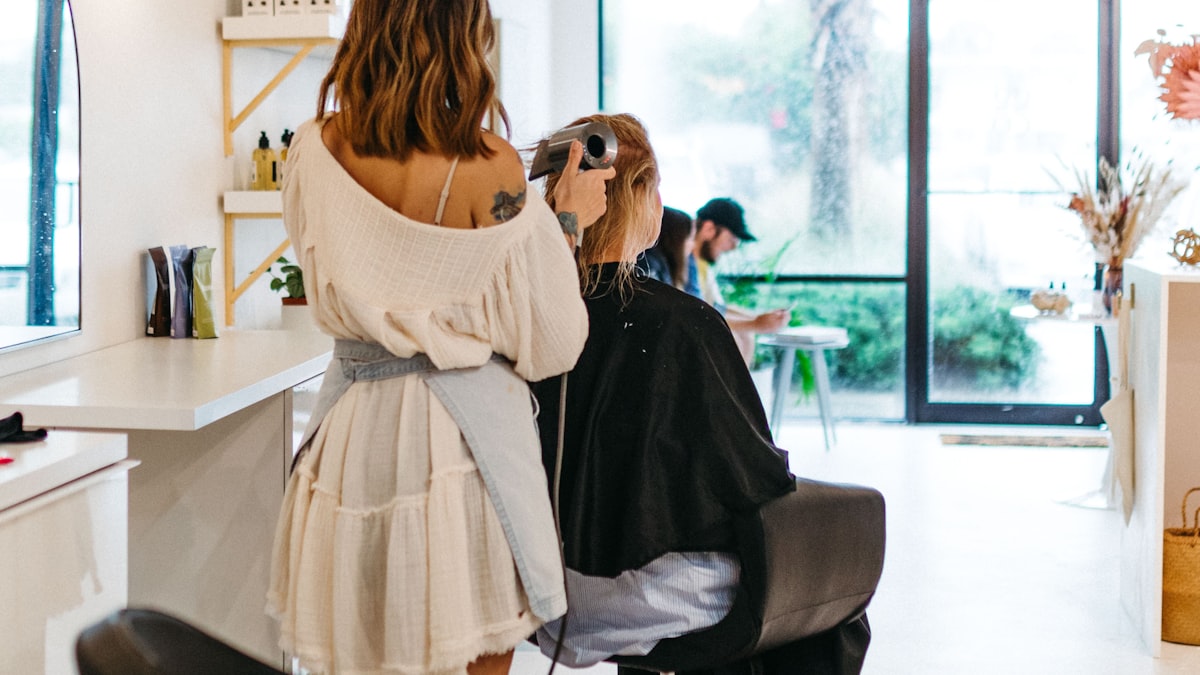 A hairstylist working on a client's hair in a bright, modern salon
